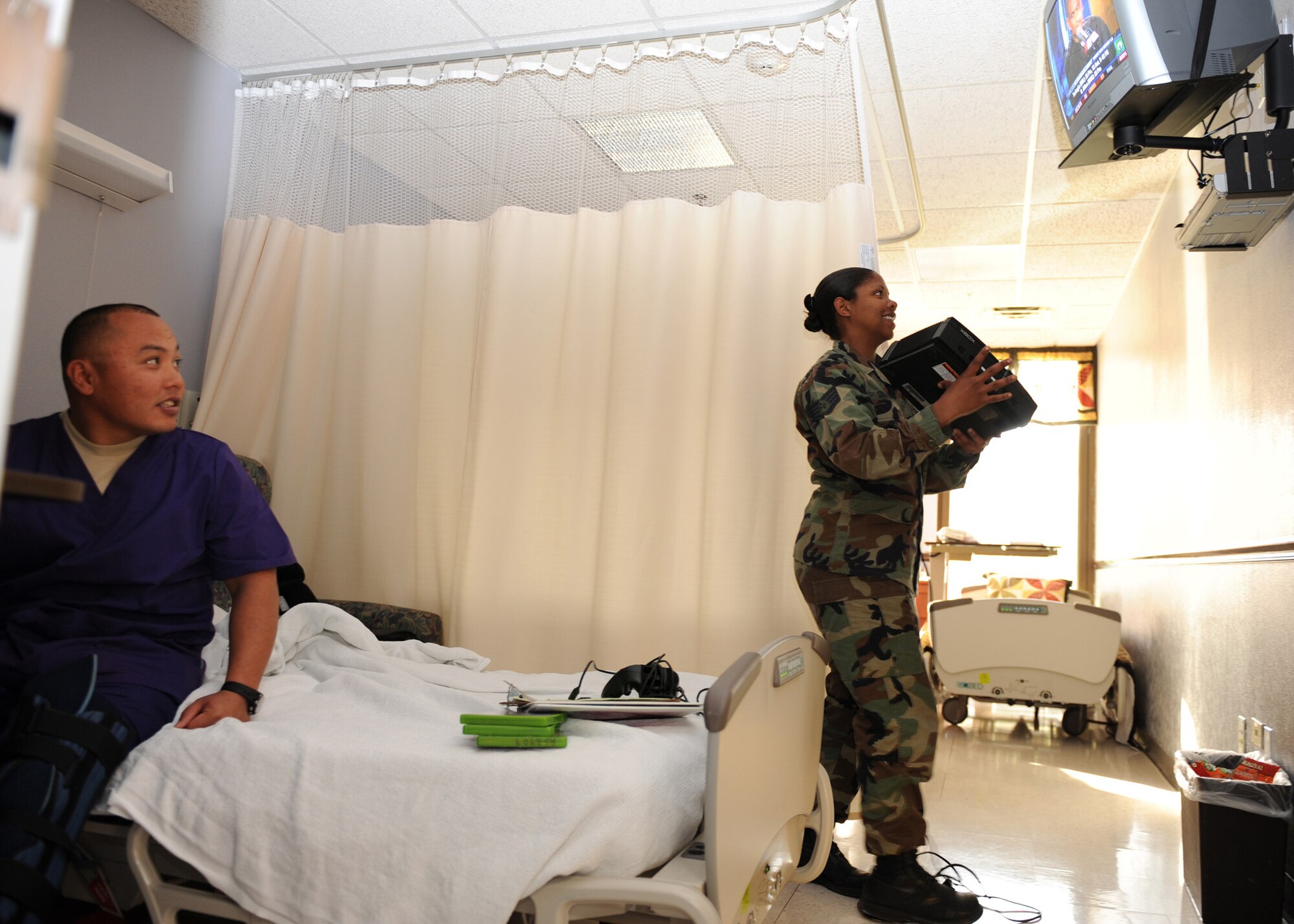 SCOTT AIR FORCE BASE, Ill. -- Spec. Herbert Pinaula, U.S. Army petroleum supply specialist, talks with Staff Sgt. Chrishana Dameron, 375th Aeromedical Staging Facility shift leader, as she connects a gaming system to his television at Scott May 18. Specialist Pinaula stopped at the Scott ASF on his return from Iraq after being injured while conducting dismounted patrols. (U.S. Air Force photo/Staff Sgt. Paul Villanueva II)