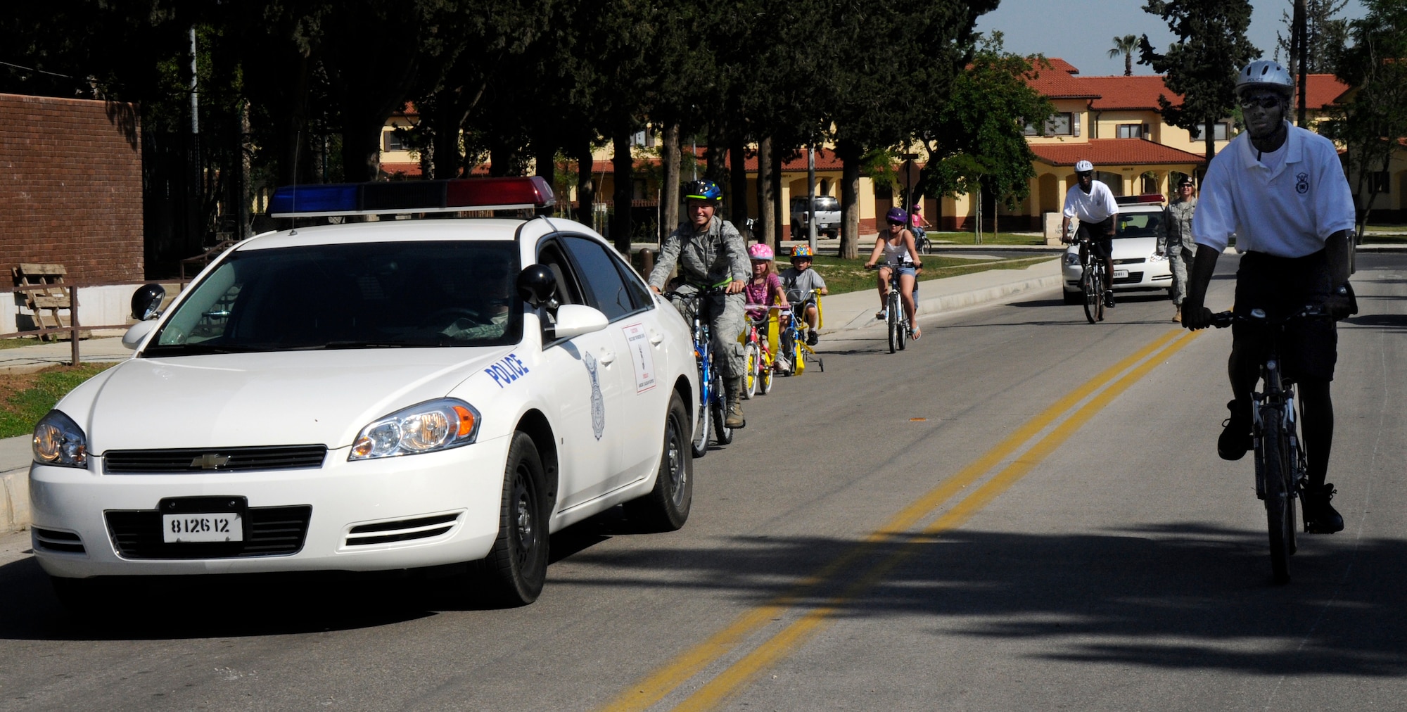Senior Airman Jarvis Beauchamp, 39th Security Forces Squadron, leads bike patrol alongside a K-9 police car, during the Police Week children’s parade May 13, 2009 at Incirlik Air Base, Turkey. The children participating learned safety tips and were taught hand signals to use while riding their bicycles. They “paraded” from the Base Exchange across base to the Security Forces building for an open house.  (U.S. Air Force photo/Airman 1st Class Amber Russell)