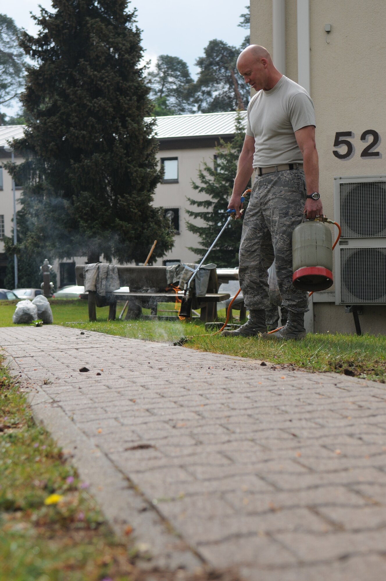 United States Air Force Chief Master Sgt. Grant McCormick, Headquarters United States Air Forces in Europe chief of training, burns weeds bordering a walkway behind his work center, Ramstein Air Base, Germany, May 11, 2009. Airmen across base worked together to pick up trash during the base clean up day. (U.S. Air Force photo by Senior Airman Levi Riendeau)