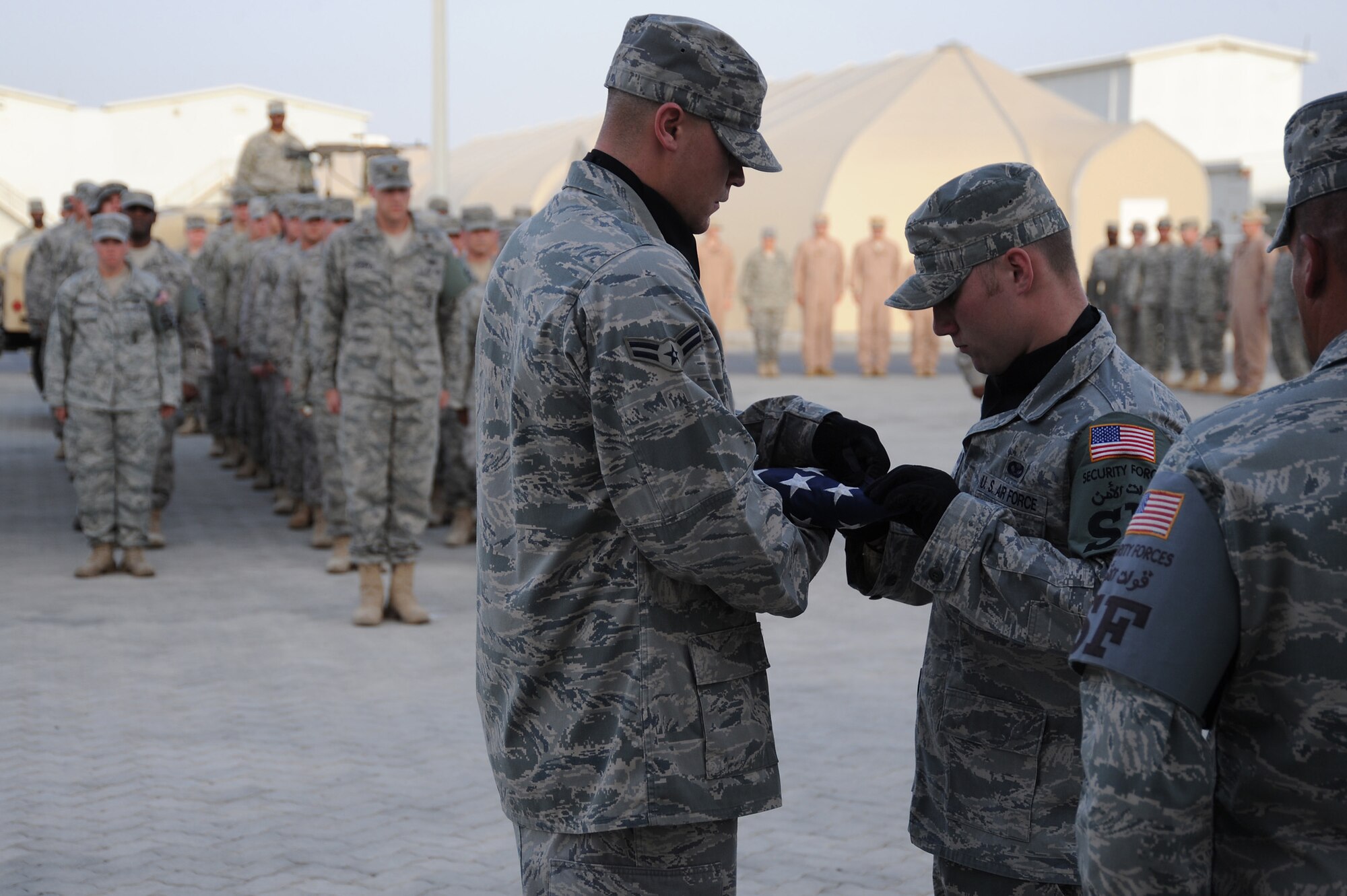 SOUTHWEST ASIA - Airman 1st Class Bryan Thomas and Airman 1st Class Chadwick Richardson, 380th Expeditionary Security Forces Squadron, retire the colors during a retreat ceremony, May 15 at an undisclosed location in Southwest Asia. The 380th ESFS and Office of Special Investigation performed the ceremony as part of National Police Week to honor the service and sacrifice of U.S. law enforcement officials. Names of fallen ESFS and OSI members were read followed by a moment of silence with the retreat ceremony concluding the event. (U.S. Air Force photo by Senior Airman Brian J. Ellis) (Released)