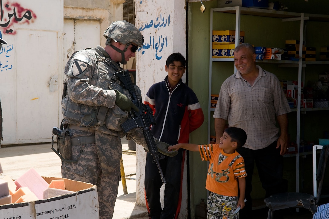 U.S. Army Capt. Nathan Jennings gives candy to an Iraqi child during a recent combined reconnaissance patrol in the industrial sector of the town of Taza, with counterparts of the Iraqi police, May 16, 2009, in Kirkuk, Iraq., Jennings is assigned to the 1st Cavalry Division's 4th Squadron, 9th Cavalry  Regiment, 2nd Heavy Brigade Combat Team.