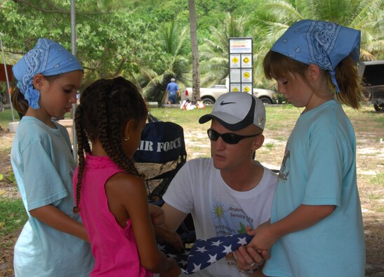 ANDERSEN AIR FORCE BASE, Guam - Staff Sgt. Noah Bolton, 36th Wing protocol office, teaches members of Brownie Troops 015 and 036 how to fold the American Flag during the first Andersen Service Unit Girl Scouts Camporee held May 16 at Tarague Beach. The flag-folding exercise was part of the badge work station where scouts could earn merit badges for their efforts. (U.S. Air Force photo by Senior Airman Shane Dunaway)