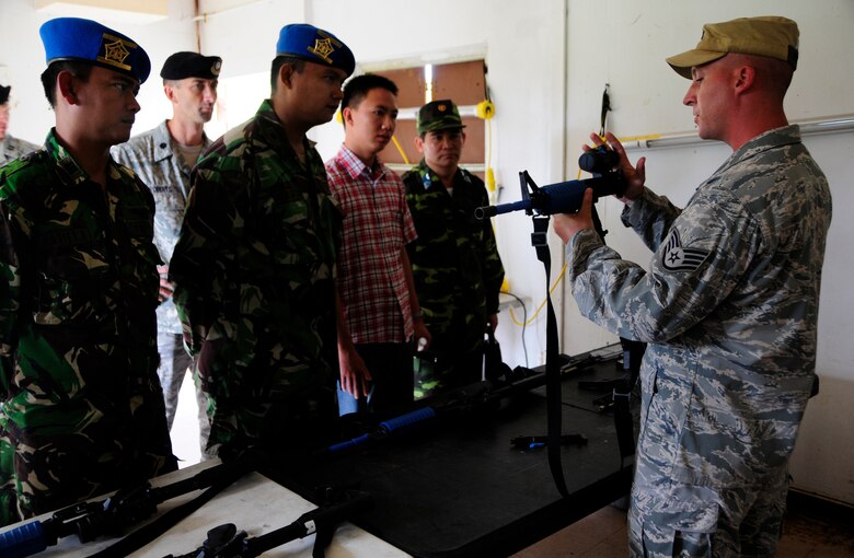 ANDERSEN AIR FORCE BASE, Guam - Staff Sgt. Timothy Hartman, 736th Security Forces Commando Warrior Cadre, demonstrates to Indonesia Capt. Tatiet Rozadi and Maj. Agung Satya Wibowo and Vietnam interpreter Mr. Cu Huy Cuong and Col. Tran Van Thuan how the M-4 simunition configured training weapons work May 19. The two countries visited Andersen as a part of the Subject Matter Expert Exchange. (U.S. Air Force photo by Airman 1st Class Courtney Witt)
