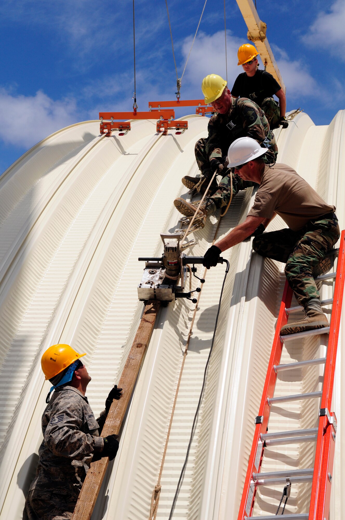 ANDERSEN AIR FORCE BASE, Guam - (From bottom) Staff Sgt. Luis Murrillo-Miranda, Senior Master Sgt. Edward Ferguson, Chief Master Sgt. Michael Scott, and Staff Sgt. Nichola Peacock all work together to seam the last section of the k-span roof together at Northwest Field May 13. All four individuals are members of the 144th Air National Guard Civil Engineer Squadron that are here for two weeks to help with the k-span building that will continue till August 1. (U.S. Air Force photo by Airman 1st Class Courtney Witt)

