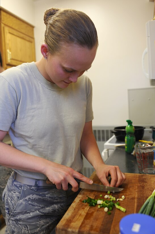 Airman 1st Class Angel Patterson, 28th Munitions Squadron ammunitions journeyman, cuts a spring onion for her Pad Thai at the Freedom Chapel here, May 19. Spring onions are just one of many ingredients to making Pad Thai, a dish from Thailand. (U.S. Air Force photo/Senior Airman Kasey Zickmund)