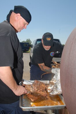 ALTUS AFB, Okla. -- Mike Proveaux and Brian King pull a brisket from the smoker to be served as part of the 2009 Rodeo lunch fundraiser.  The lunch raised over $1,600 to help offset the cost of promotional items associated with sending the team in July. (U.S. Air Force photo by Tech. Sgt. Brian M Boisvert)