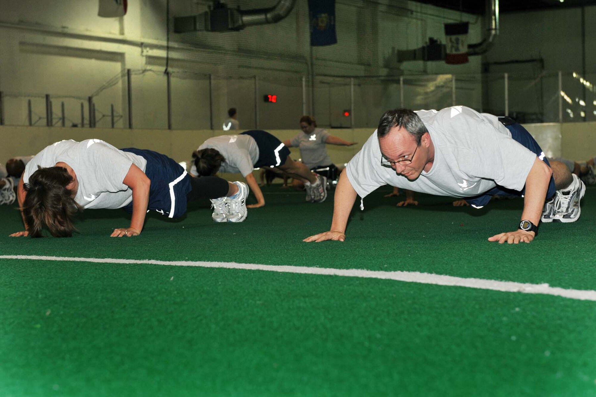 OFFUTT AIR FORCE BASE, Neb. -- Col. Robert L. Maness, 55th Wing vice commander, and members of the Fightin' Fifty-Fifth perform wide-body-push-ups during physical training at the Offutt Field House May 15. Physical training helps prepare personnel for their annual PT test and helps ensure they're "fit to fight." U.S. Air Force photo by Charles Haymond