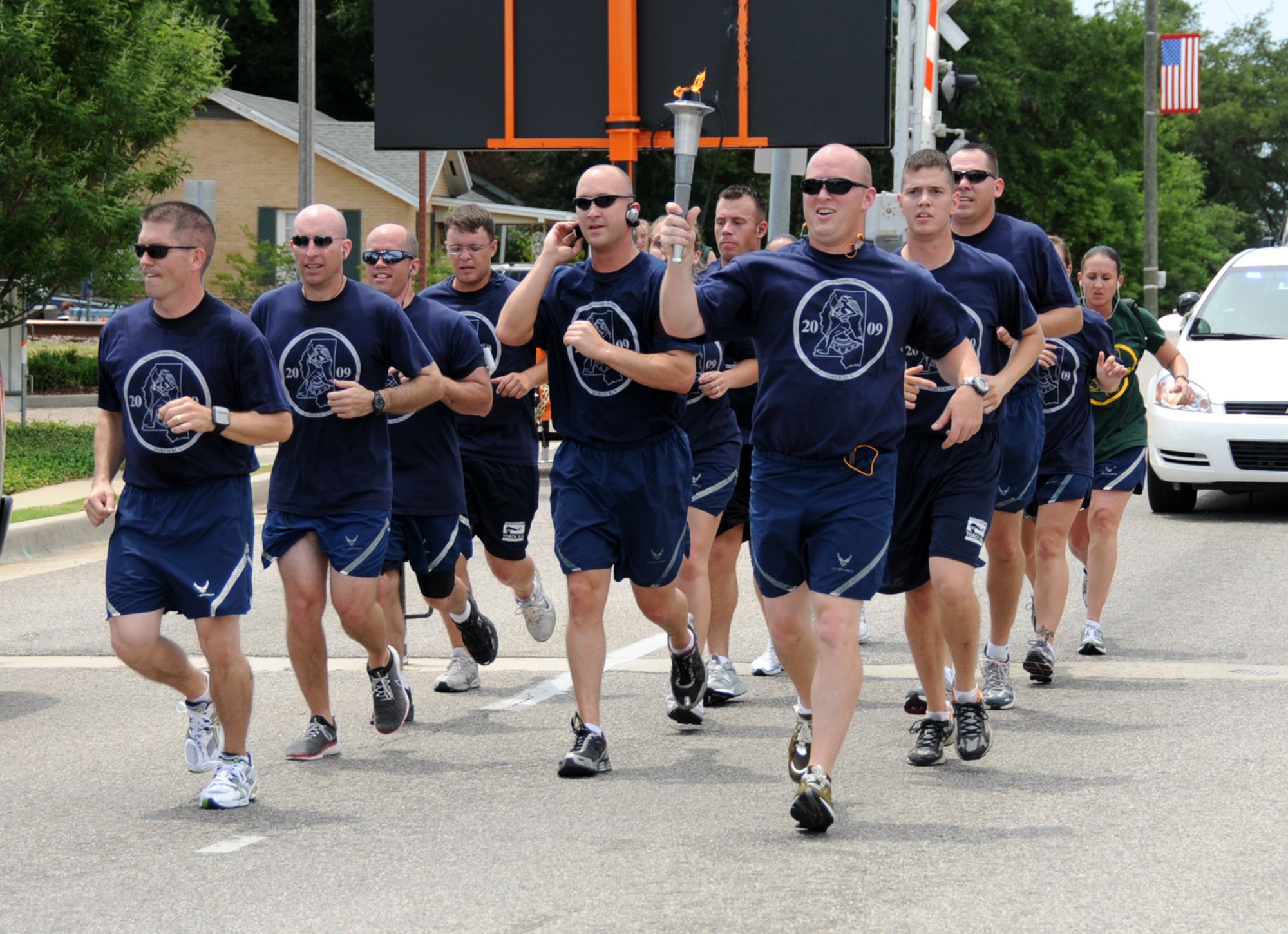 Chief Master Sgt. Alex Perry, left, 81st Training Wing command chief, and members of the 81st Security Forces Squadron bring the Special Olympics torch through the gate at White Avenue Friday.  (U.S. Air Force photo by Kemberly Groue)