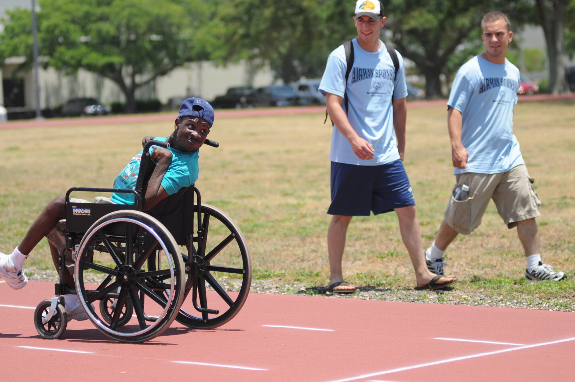 Area 12 athlete David Beckham takes off down the Triangle track backwards in the 25-meter wheelchair race with the encouragement of his sponsors, Airmen Basic Joseph Garcia and David Trott, 334th TRS.  (U.S. Air Force photo by Kemberly Groue)
