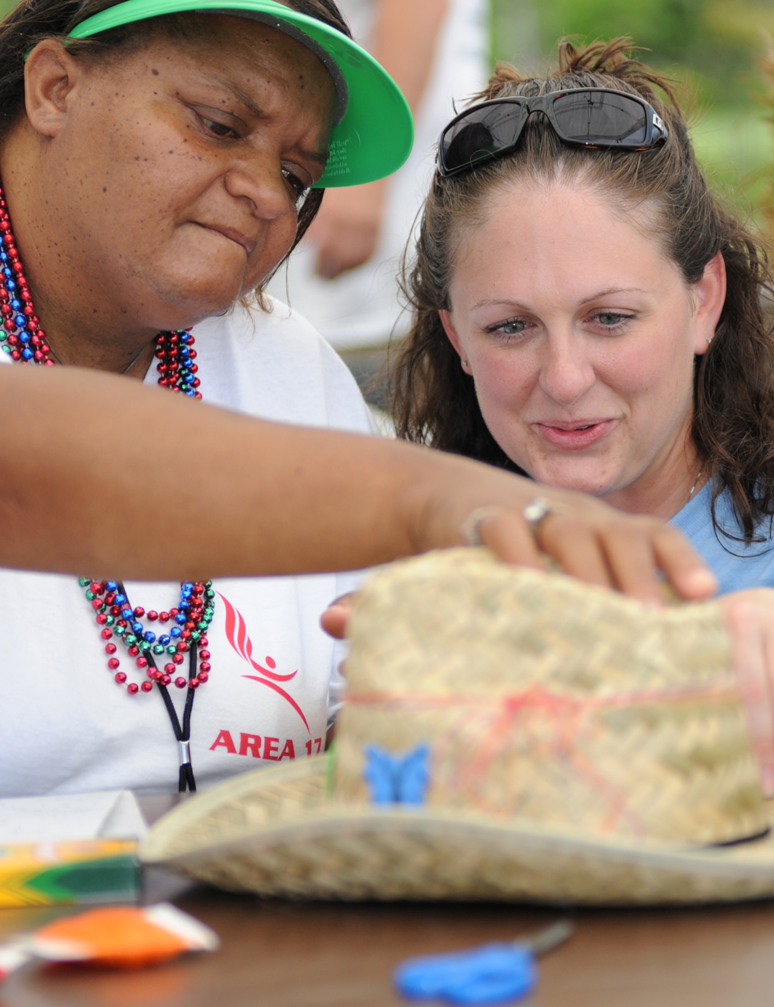 Area 17 athlete Donna Husband and her sponsor, Airman Basic Natalie Ricketts, 332nd TRS, decorate hats at the Olympic Village Saturday.  (U.S. Air Force photo by Kemberly Groue)