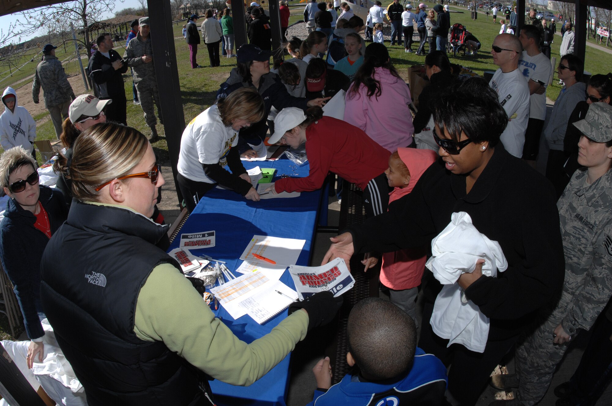 MINOT AIR FORCE BASE, N.D. -- Danielle Helstedt, sports coordinator for the David C. Jones Youth Center, hands T-shirts and race numbers to Nikki Wylder here prior to the Why Not Run event here May 16. The event was hosted by the 5th Force Support Squadron to promote physical fitness and team building.  (U.S. Air Force photo by Staff Sgt. Angel Gallardo)