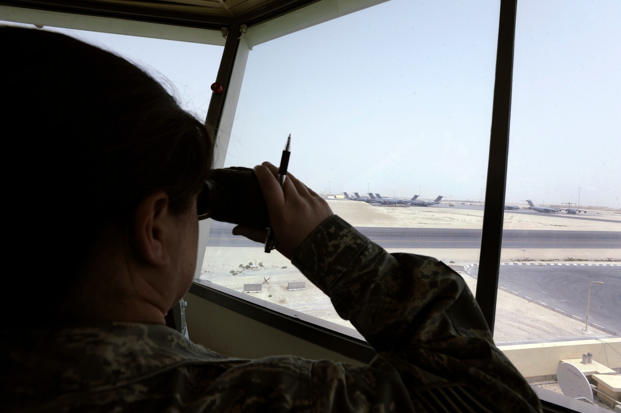 Tech. Sgt. Tracy McDonald, the tower watch supervisor for the 379th Expeditionary Operations Support Squadron, watches as a C-17 Globemaster III leaves the main ramp to taxi to the runway for takeoff here, May 18, 2009, in an undisclosed location in Southwest Asia.  Sergeant McDonald and fellow air traffic controllers, use binoculars to monitor everything on the flightline from moving aircraft to support equipment and foreign object debris.  Sergeant McDonald is native to Tickfaw, La. and is deployed from Alexandria Air National Guard Base, La., in support of Operations Iraqi and Enduring Freedom and Combined Joint Task Force - Horn of Africa.  (U.S. Air Force Photo by Staff Sgt. Joshua Garcia/released)