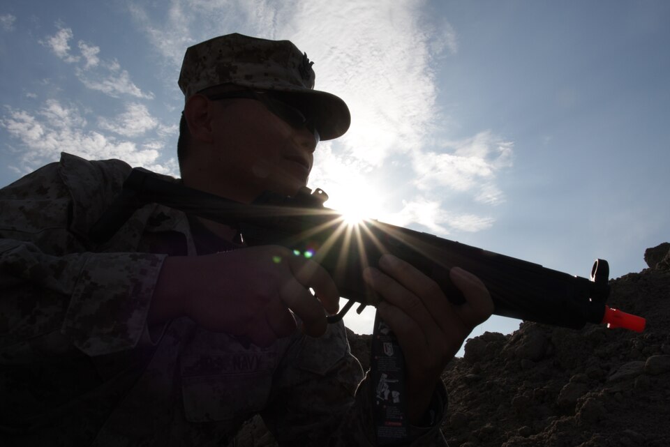 Petty Officer 2nd Class, a hospital corpsman with 3rd Battalion, 4th Marine Regiment, playing an enemy aggressor, sits waiting to ambush unsuspecting corpsmen on patrol.