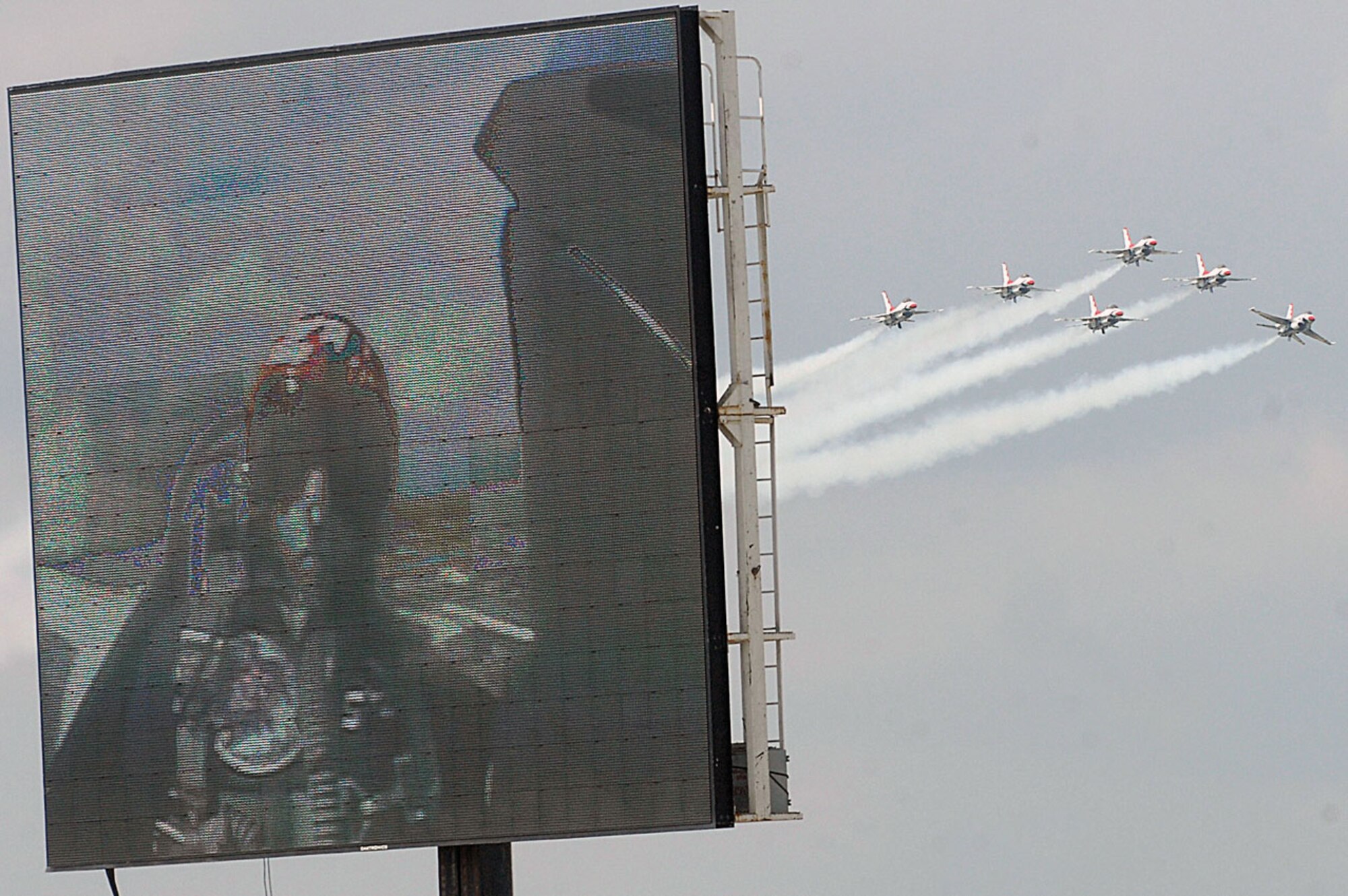 The Thunderbirds fly in formation as the Jumbo-Tron displays Lt. Col. Greg Thomas, Thunderbirds commander, during the JSOH May 16. (U.S. Air Force photo/ Senior Airman Giang Nguyen)