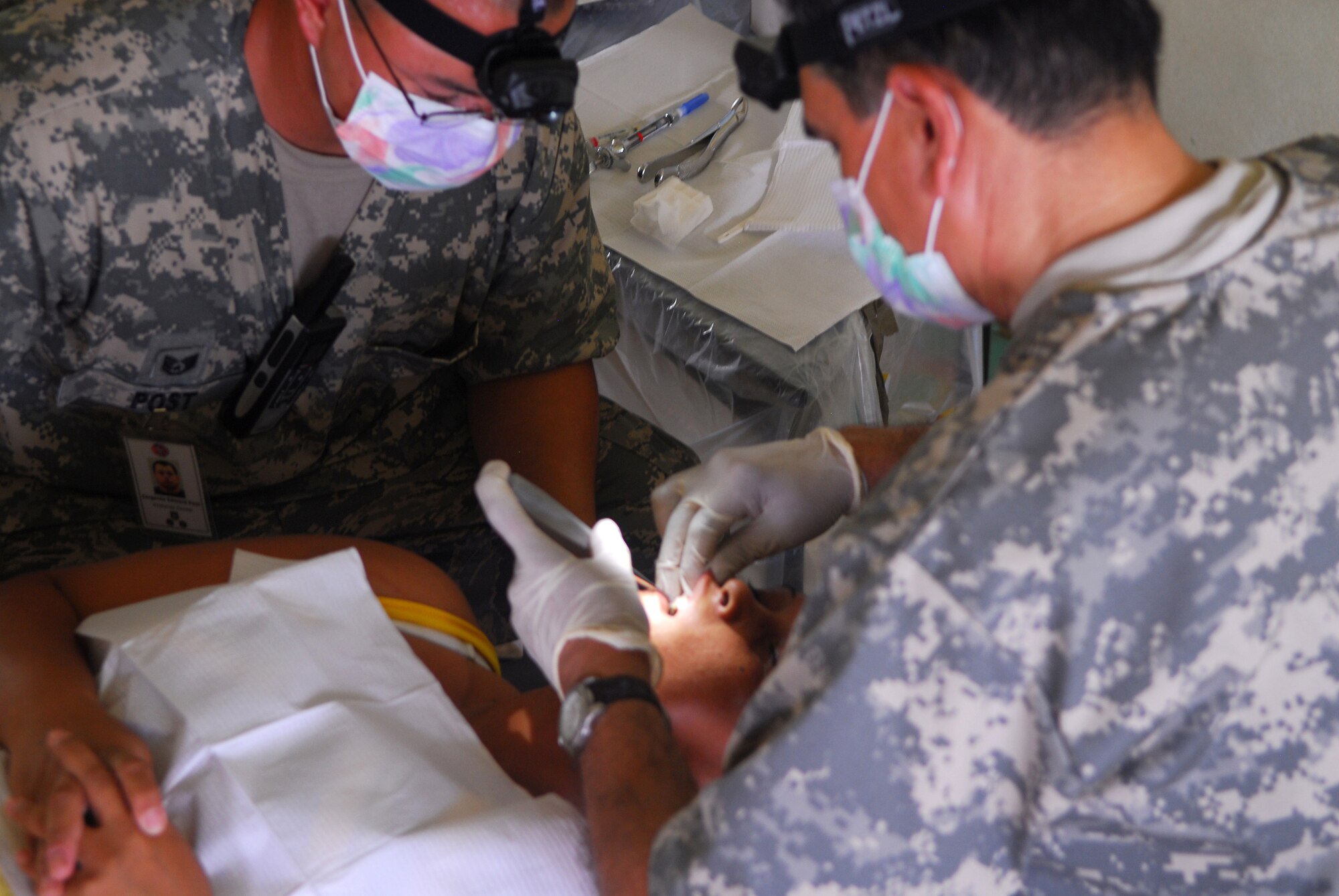ALAJUELA, Costa Rica -- Staff Sgt. Edward Post, a 30th Medical Operations Squadron dental assistant, holds the hand of a Costa Rican woman as Lt. Col. Guy Delgadillo, the 30th MDOS dental flight commander, performs an oral cleaning May 19 at a local school house here. A team of medical specialists from Vandenberg is contributing to a humanitarian effort with local Costa Rican physicians to provide medical care to residents who are rarely seen by physicians due to living in isolated areas. (U.S. Air Force photo/Airman 1st Class Steve Bauer)
