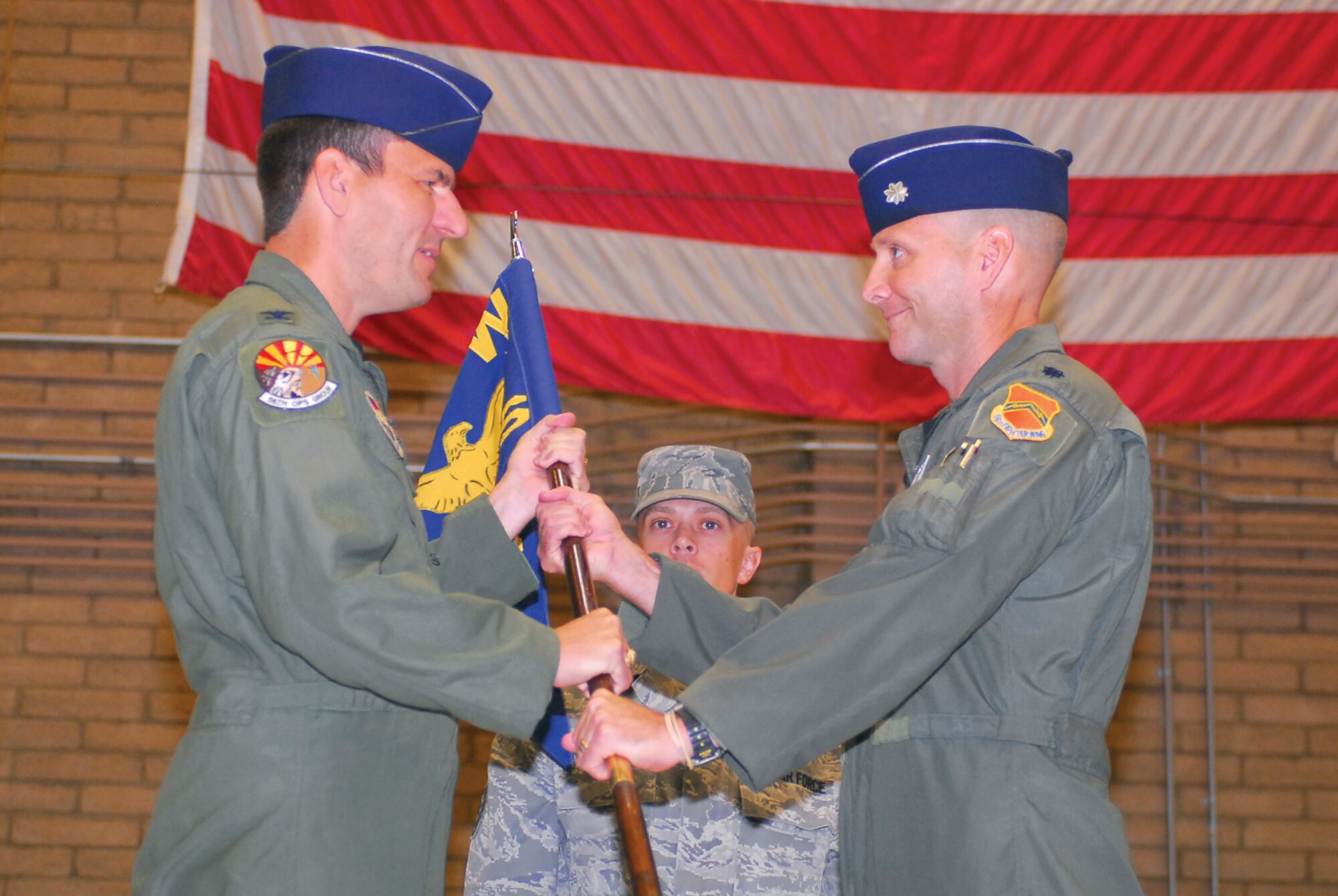 Col. Pete Schaub, 56th Operations Group commander, presents Lt. Col. Jeffrey Jenssen, 308th Fighter Squadron commander, the unit guidon during the 308th FS change-of-command ceremony May 14 in Hangar 485. (U.S. Air Force photo/ Airman 1st Class Tracie Forte)
