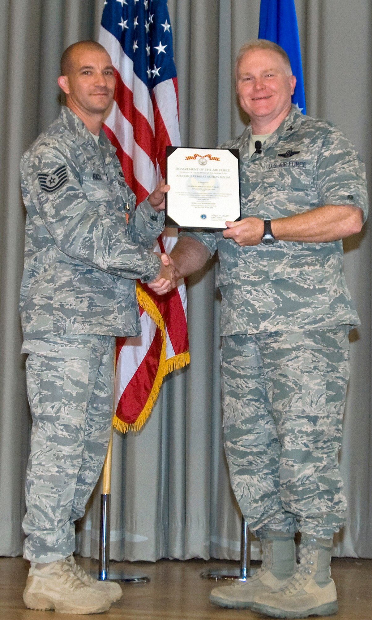 Col. Jerry Gandy, 95th Air Base Wing commander, presents Tech. Sgt. John Ricci, 95th Security Forces Squadron patrolman, with a Bronze Star Medal during a commander's call in the base theater May 14. Sergeant Ricci received the award for his deployment to Iraq. (U.S. Air Force photo/Heather Anhalt)