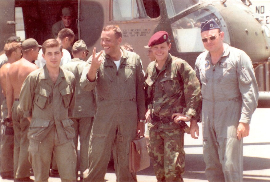 As fellow service members go over their battle-damaged helicopter, checking out the bullet holes, the Jolly 15 crew poses for a picture. The team was assigned to the 37th Air Rescue and Recover Service in 1969, from left, Airman James Thibodeau, Capt. Martin Reichert, Airman Dennis Palmer and Capt. Pete Hall. 