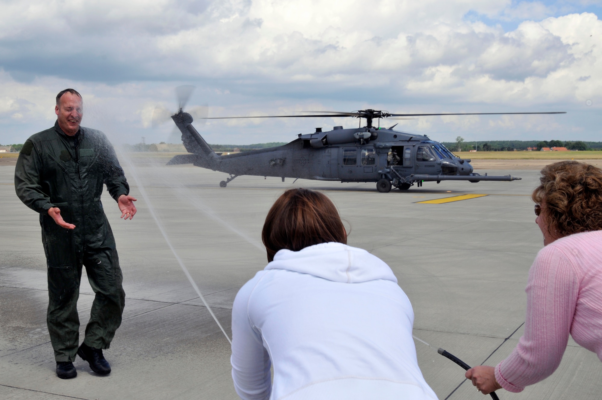 Wife Kammi and daughter Tiffany spray Master Sgt. Darren Bradley, 56th Rescue Squadron HH-60G flight engineer, with water May 21, 2009 at Royal Air Force Lakenheath, England. Sergeant Bradley celebrated his 5,000th flying hour in a HH-60G. (U.S. Air Force photo by Airman 1st Class Perry Aston) 