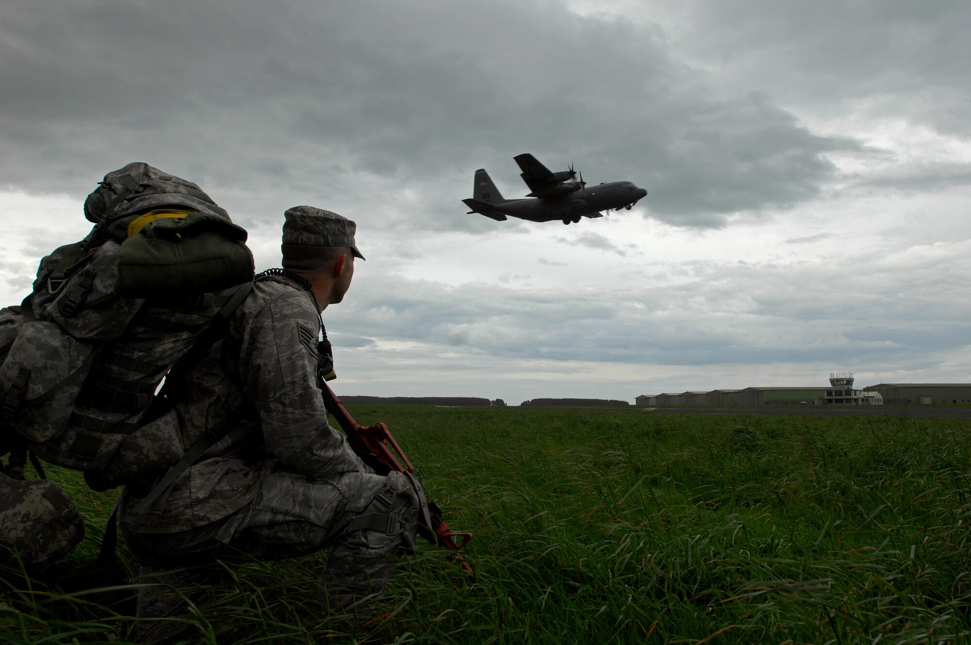 United States Air Force Staff Sgt Jason Schaffer, 786th Security Forces Squadron Paratrooper takes a knee as a C-130 Hercules flies overhead after departing West Freugh Airfield, Scotland during an Operational Readiness Exercise, May 18, 2009. (U.S. Air Force photo by Senior Airman Kenny Holston)