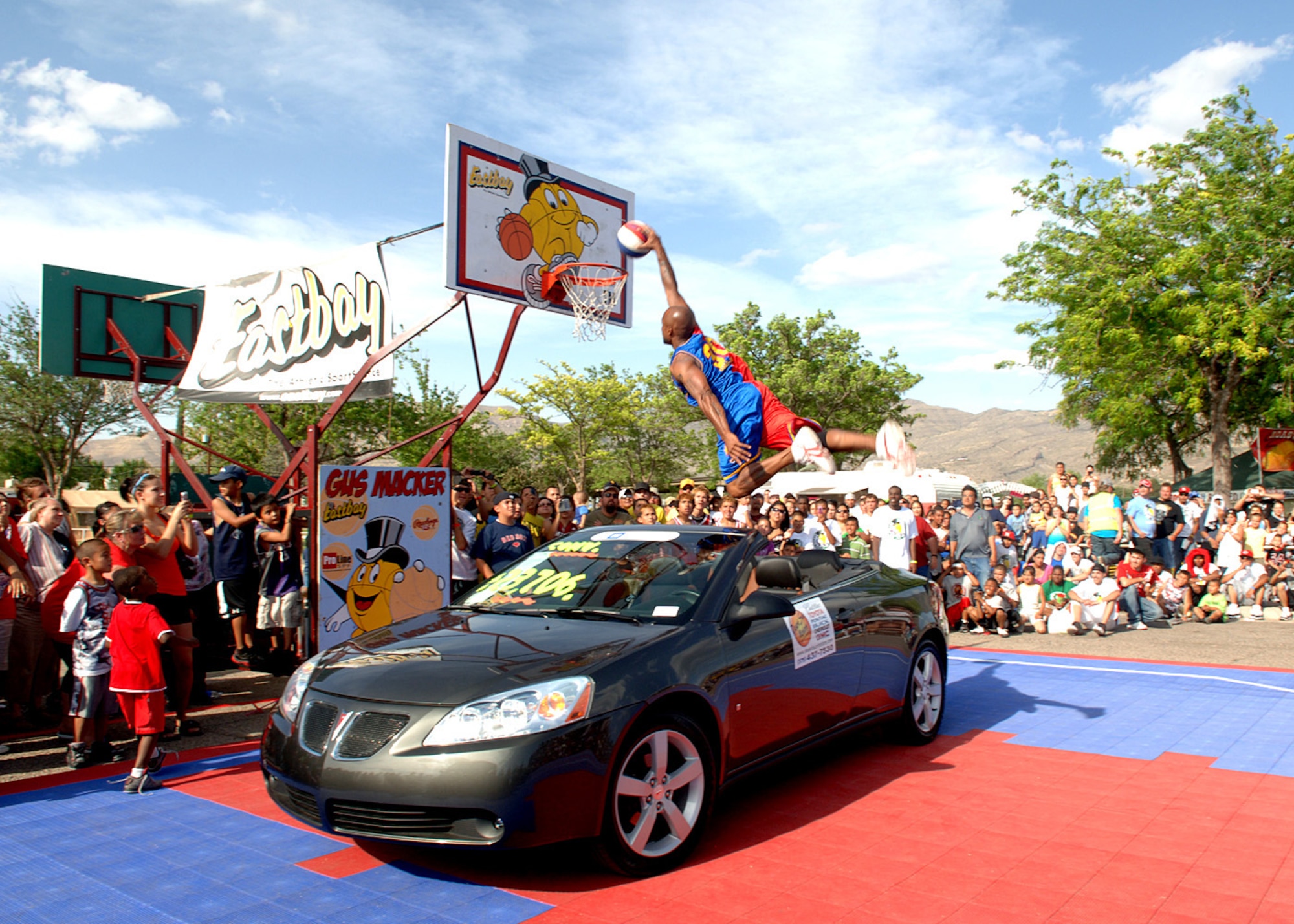 Wayne "Air Royal" Clark, #30 Harlem Starz  slams dunk over a 2007 Pontiac G6 sponsored by Desert sun Toyota, for Saturday in the Park/Armed Forces Day at Washington Park in Alamogordo, N.M., May 15. All Gus Macker teams from around New Mexico gather around the court to watch. (U.S. Air Force photo/ Airman 1st Class Veronica Stamps)