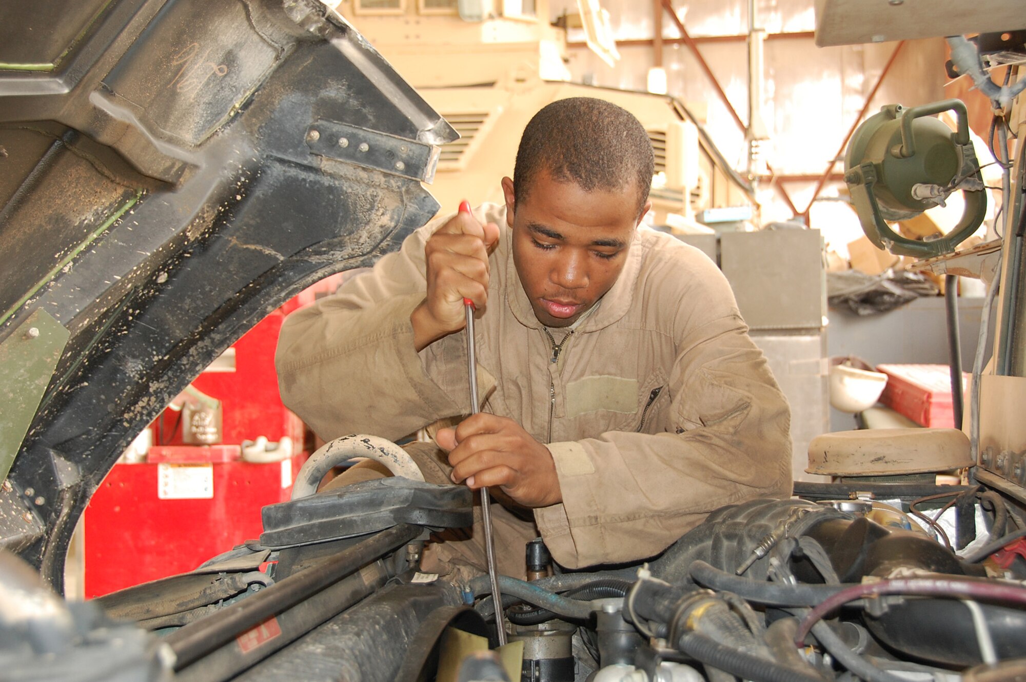 CAMP BUCCA, Iraq -- Senior Airman Marcel Edwards, 887th Expeditionary Security Forces Squadron vehicle technician, works on a humvee engine at the Camp Bucca motor pool May 11. Four Airmen from the 887th ESFS work alongside Army vehicle maintainers to keep the squadron’s MRAPs and humvees and other camp vehicles working. (U.S. Air Force photo by Staff  Sgt. Thomas J. Doscher)