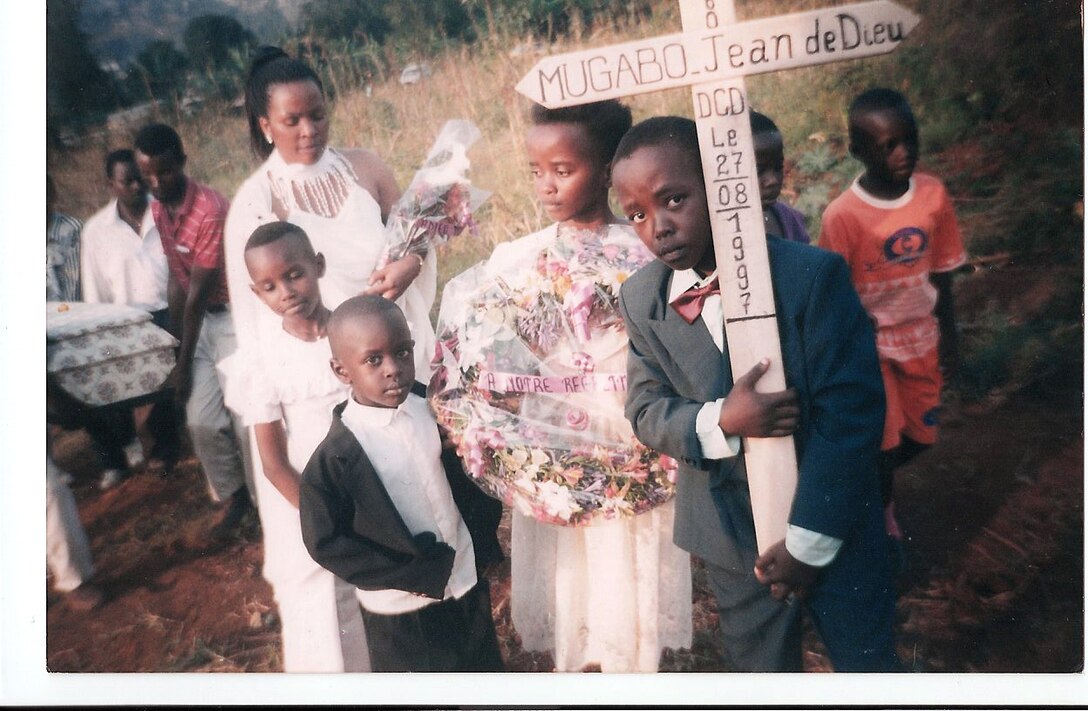 Lance Cpl. Pierre Mugabo carries his father's cross, used as a grave marker, during funeral proceedings two days after his fathers death. Mugabo's father died of malnutrition while in a prision camp. After his death, Mugabo's mother moved him and his sister to the United States.