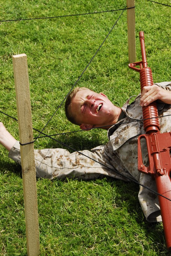 Cpl. Stolf Short, a Marine Corps Air Station Yuma, Ariz. Search and Rescue maintenance administrator, crawls under simulated barbed wire after being sprayed with Oleoresin Capsicum during a martial arts instructor course May 21, 2009.(Photo by Cpl. Laura A. Mapes)