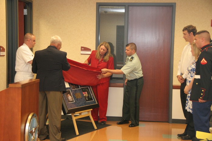 Pfc. Ryan M. Jerabek's mother and father, along with leadership from the Milwaukee Military Entrance Processing Station, unveil a memorial display outside the ceremonial oath room dedicated to Jerabek here May 22. Jerabek took the oath of enlistment in that same room in 2002 at the age of 17, and just two years later, he made the ultimate sacrifice protecting his fellow Marines while on combat operations in Ramadi, Iraq. (Official U. S. Marine Corps photo by Staff Sgt. Greg Thomas)