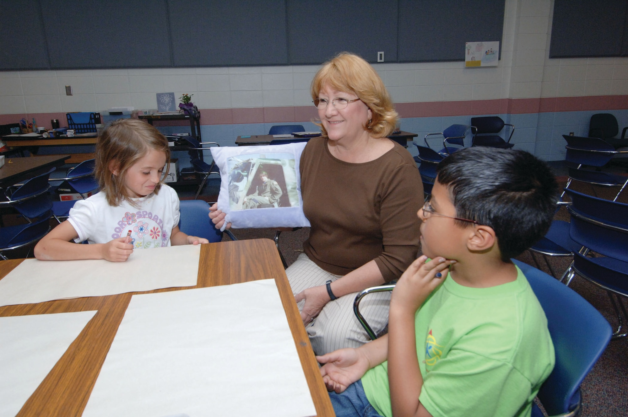 Maxwell Elementary School Counselor, Mary Jo Ryan, shows two members of her "Far and Away Club" a pillow that she's designed to help children remember their deployed parents. At left is first-grader Shailah Lowe and also shown is second-grader Ahrian Davis. (U.S. Air Force photo/Melanie Rodgers Cox)