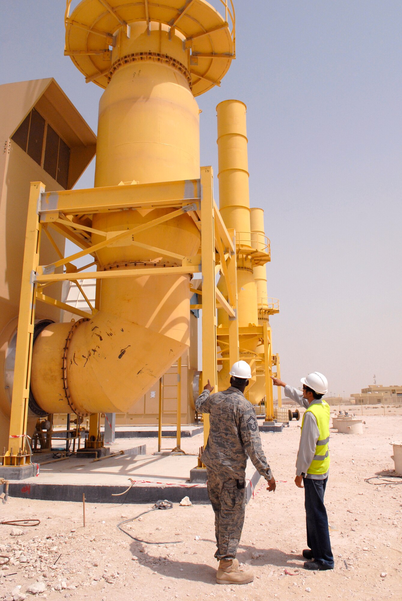 Mel Malinas, electrical engineer, shows parts of the gas-fired turbine and explains the functionality of the new power plant to Senior Master Sgt. Freddie Flowers, 379th Expeditionary Civil Engineer Squadron Superintendent of electrical and infrastructure, during a walk-through of the power plant, May 21, 2009, at an undisclosed location in Southwest Asia.  The power plant will save millions of dollars annually and help transform the base from expeditionary to enduring.  Mr. Malinas hails from Cavite, Philippines and is deployed as a contractor here.  Sergeant Flowers hails from Lakeland, Ga. and is deployed here from Yokota Air Base, Japan.  Both are deployed in support of Operations Iraqi and Enduring Freedom and Combined Joint Task Force - Horn of Africa.  (U.S. Air Force photo/Senior Airman Andrew Satran/released)