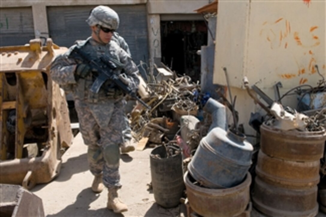 U.S. Army 1st Lt. Jacob Lopez, attached to Crazy horse Troop, 4th Squadron, 9th Cavalry Regiment, 2nd Heavy Brigade Combat Team, 1st Cavalry Division inspects barrels filled with car parts during a recent combined reconnaissance patrol with counterparts of the Iraqi Police in the industrial sector of the town of Taza, in Kirkuk, Iraq, on May 16, 2009.  