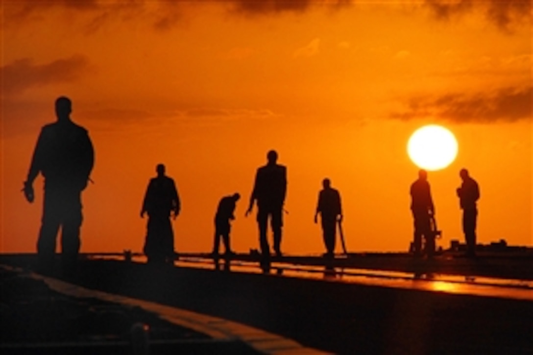 U.S. Navy sailors stand on the deck against the setting sun at the end of flight operations aboard the USS George H.W. Bush in the Atlantic Ocean, May 21, 2009.