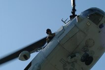 The crew chief of a CH-46E from Marine Medium Helicopter Squadron 774, here as part of Special Purpose Marine Ground Task Force New York checks the landing zone at Orchard Beach in the Bronx May 22 during a Fleet Week helicopter raid demonstration. (Official Marine Corps photo by Lance Cpl. Jad Sleiman)