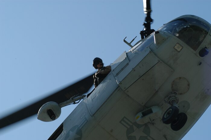 The crew chief of a CH-46E from Marine Medium Helicopter Squadron 774, here as part of Special Purpose Marine Ground Task Force New York checks the landing zone at Orchard Beach in the Bronx May 22 during a Fleet Week helicopter raid demonstration. (Official Marine Corps photo by Lance Cpl. Jad Sleiman)