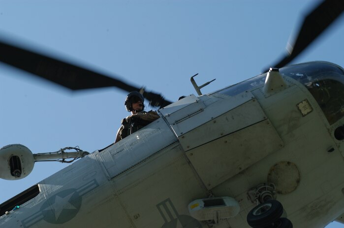 The crew chief of a CH-46E from Marine Medium Helicopter Squadron 774, here as part of Special Purpose Marine Ground Task Force New York checks the landing zone at Orchard Beach in the Bronx May 22 during a Fleet Week helicopter raid demonstration. (Official Marine Corps photo by Lance Cpl. Jad Sleiman)