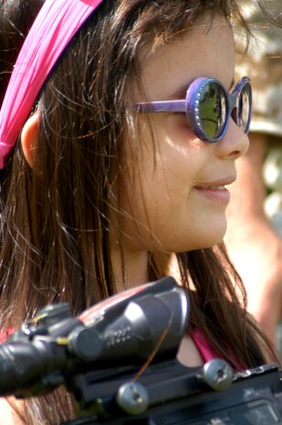 Brianna Mateus of New Rochelle, N.Y. smiles at a Marine from Marine Medium Helicopter Squadron 774, Special Purpose Marine Air Ground Task Force New York as she holds an M16 M4 assault rifle during the meet and greet portion of a helicopter raid demonstration at Orchard Beach in the Bronx May 22. (Official Marine Corps photo by Lance Cpl. Jad Sleiman)