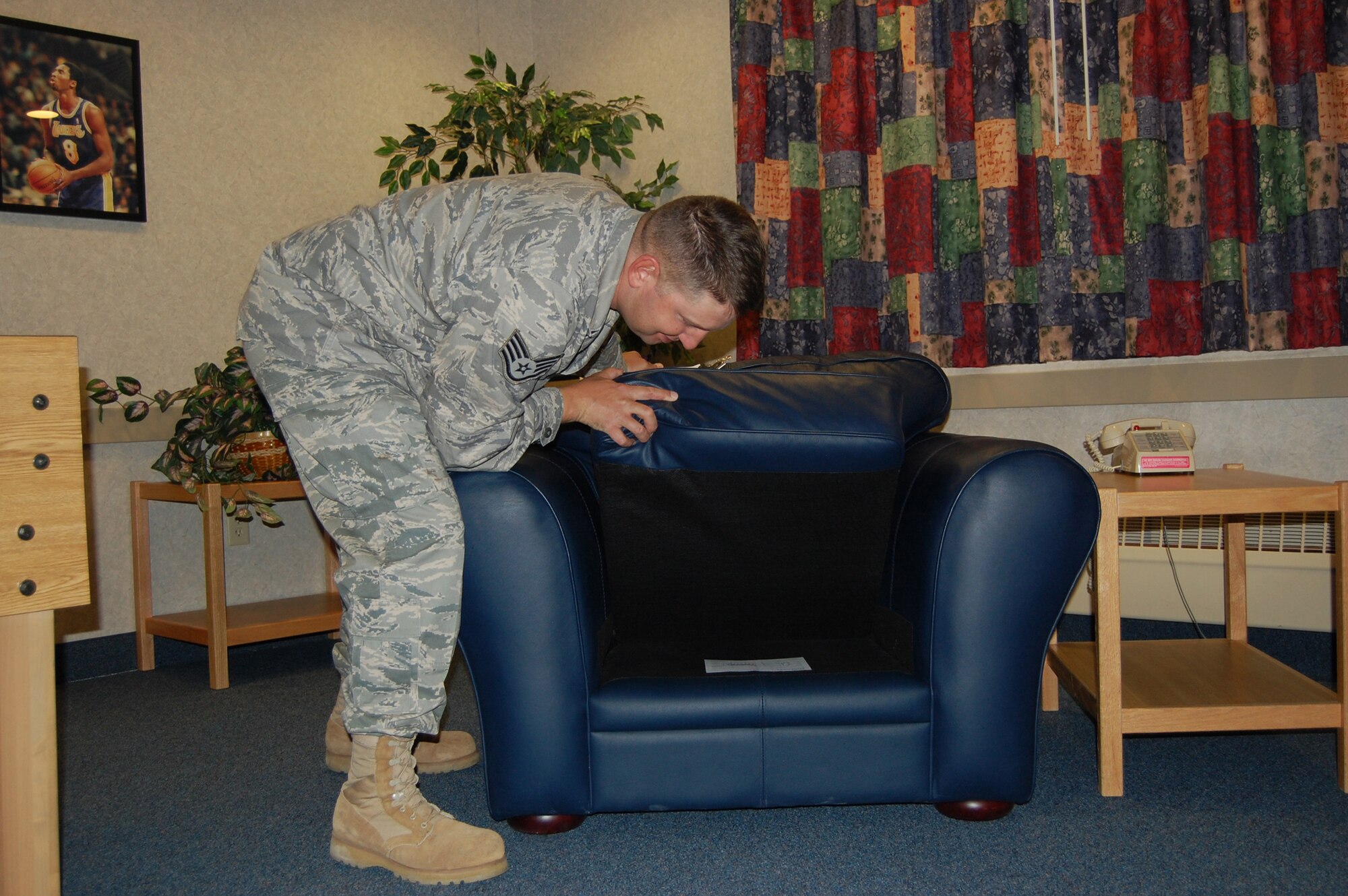 Staff Sgt. Terry Hendricks checks under the cushions of a chair in the Bldg. 764 first floor day room. Sergeant Hendricks is a dormitory manager and part of his duties are to perform inspections three times a week as part of the U-Kleen program. He is assigned to the 219th RED HORSE Squadron. (U.S. Air Force photo/Valerie Mullett)