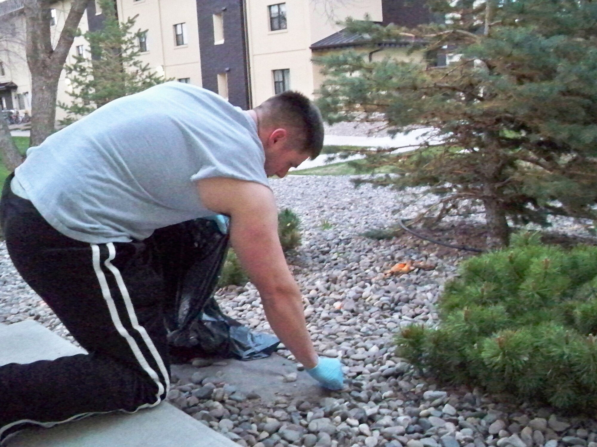 Airman Christopher Thein, 341st Missile Maintenance Squadron,  picks up trash from the landscaping around his dormitory, building 764, as part of his duties under the U-Kleen Program. (U.S. Air Force courtesy photo)
