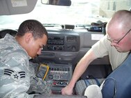 SEYMOUR JOHNSON AIR FORCE BASE, N.C. -- Senior Airman Christopher Twitty (left) and Senior Airman Stephen Roshong install a mobile radio inside an ambulance while deployed to Al Udeid Air Base, Qatar. Airman Twitty is a radio maintenance specialist with the 916th Air Refueling Wing, Air Force Reserve and Airman Roshong is a member of the 4th Fighter Wing Communication Squadron.