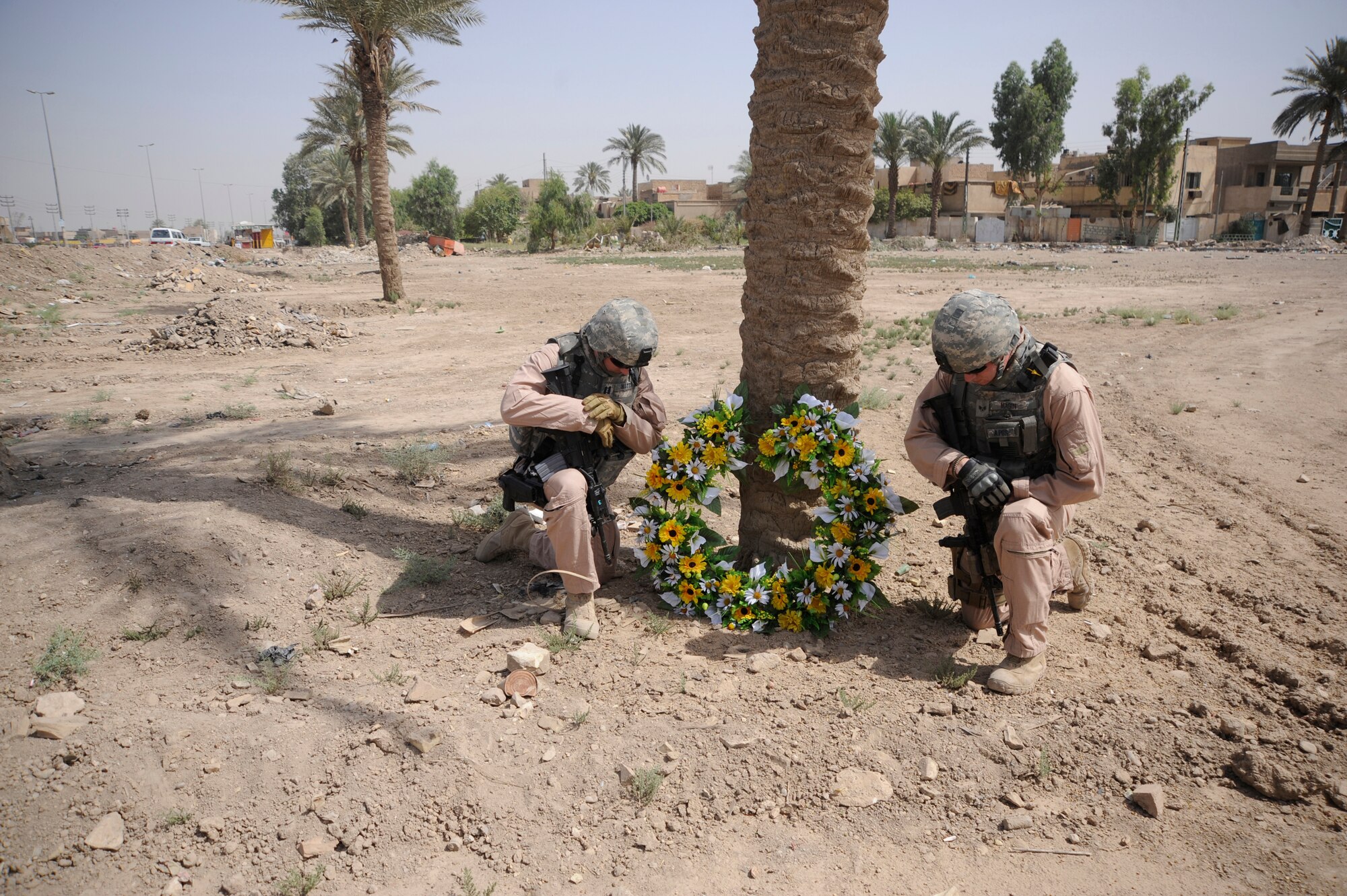 Left, U.S. Air Force Capt. David Watts and Senior Airman Cole Magin pray beside a  wreath May 14, placed as a memorial for Staff Sgt. John T. Self, who was killed in action two years ago on this date when an Improvised Explosive Device struck his vehicle. Captain Watts and Airman Magin served with Sergeant Self and are currently deployed in support of Operation Iraqi Freedom.  (U.S. Air Force Photo by Staff Sgt. Shawn Weismiller)