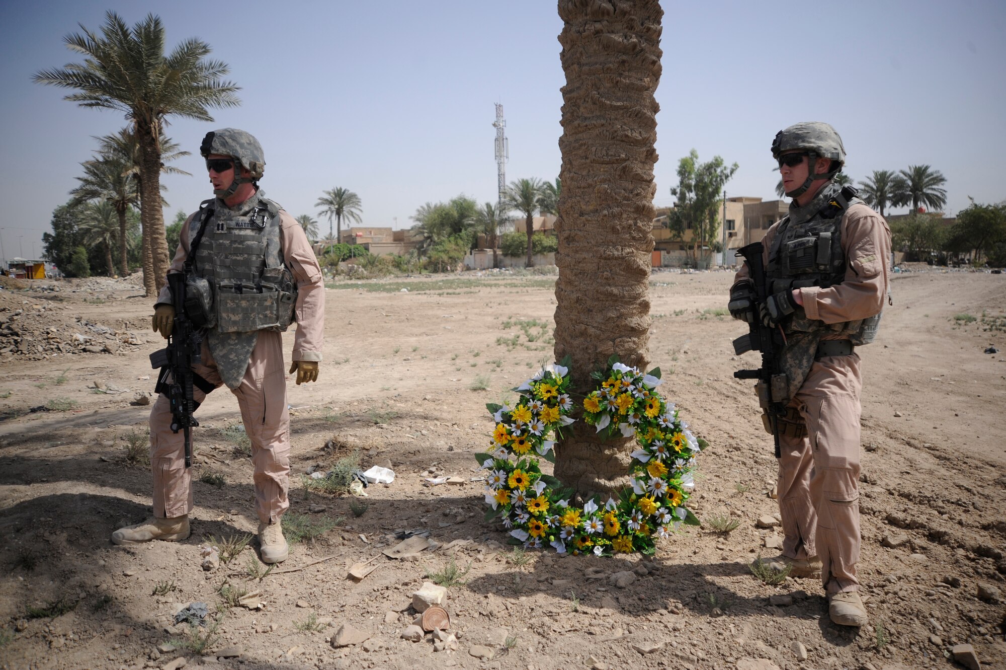 Left, U.S. Air Force Capt. David Watts and Senior Airman Cole Magin stand beside a  wreath May 14,  placed as a memorial for Staff Sgt. John T. Self, who was killed in action two years ago on this date when an Improvised Explosive Device struck his vehicle. Captain Watts and Airman Magin served with Sergeant Self and currently are deployed in support of Operation Iraqi Freedom.  (U.S. Air Force Photo by Staff Sgt. Shawn Weismiller)