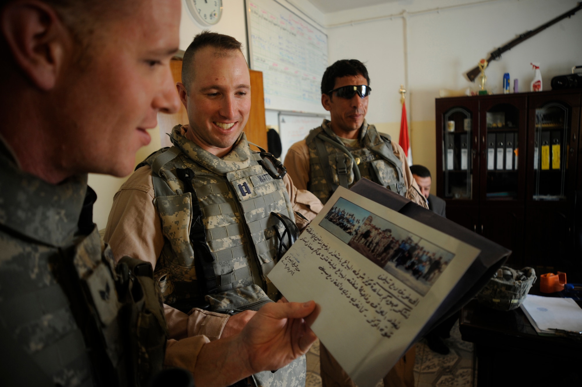 U.S. Air Force Capt. David Watts and Senior Airman Cole Magin reminisce as they look at pictures on a plaque used as a memorial for Staff Sgt. John T. Self, who was killed in action two years ago May 14 when an Improvised Explosive Device struck his vehicle. Captain Watts and Airman Magin served with Sergeant Self and currently are deployed in support of Operation Iraqi Freedom.  (U.S. Air Force Photo by Staff Sgt. Shawn Weismiller)