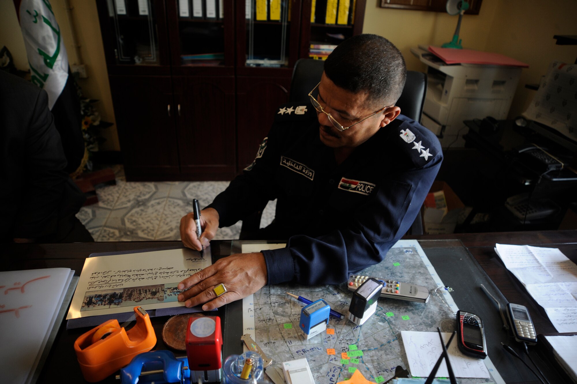 The Al Baya District Iraqi Police Station Commander signs a plaque which will serve as a memorial for Staff Sgt. John T. Self, who was killed in action two years ago May 14 when an Improvised Explosive Device struck his vehicle.  (U.S. Air Force Photo by Staff Sgt. Shawn Weismiller)