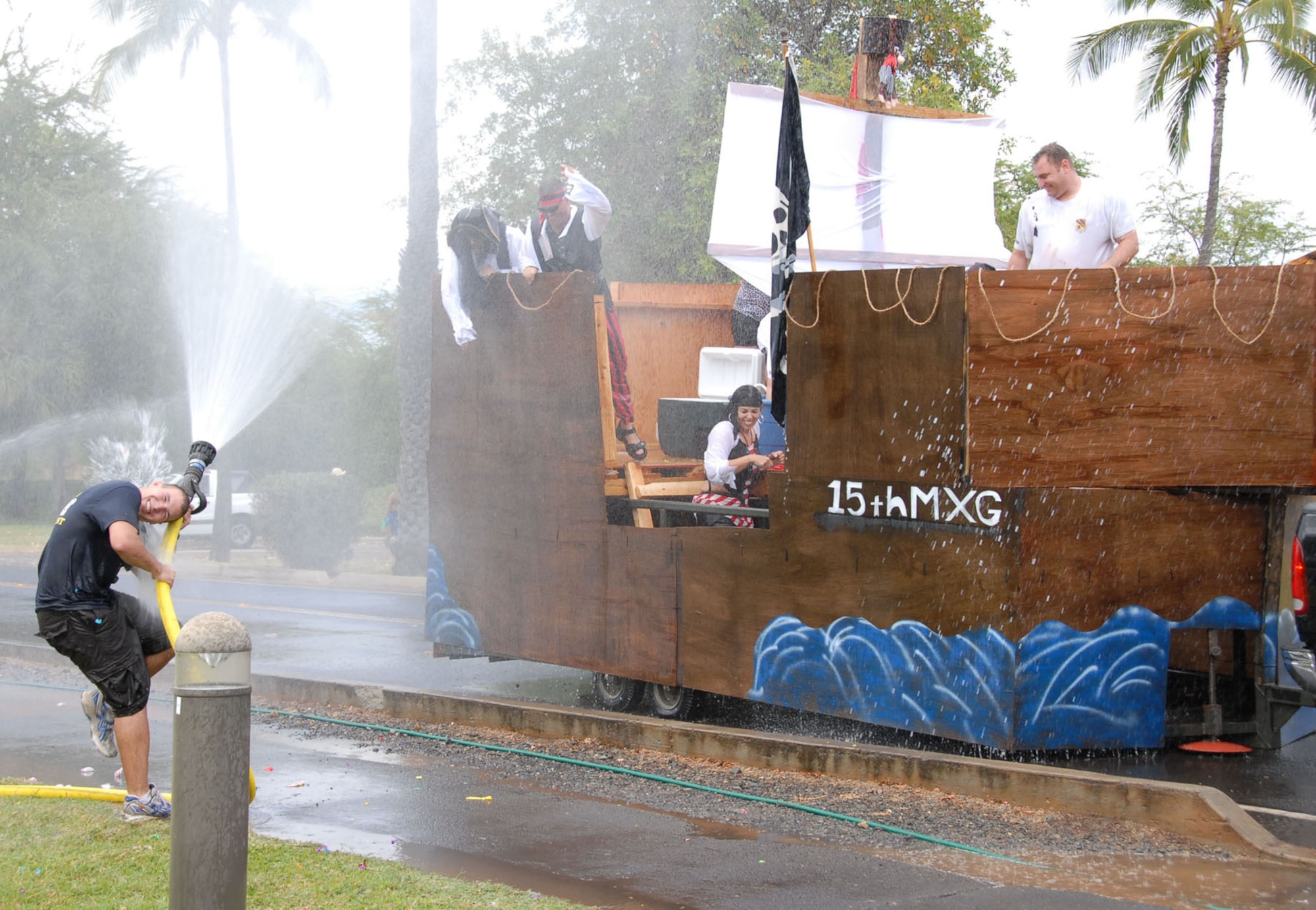 HICKAM AIR FORCE BASE, Hawaii -- Senior Airman Curtis Billig, 15th Civil Engineer Squadron fire prevention element fire protection specialist, "fights" members of the 15th Maintenance Group's Pirate Float during the annual Beach Bum Parade float contest at Hickam Harbor May 23. Beginning at Bishop Point pier, the floats passed the Hickam Fire Department, which had fire hoses hooked up to soak the occupants. Spectators were armed with water balloons, and float members defended themselves with huge water guns. The Hickam Community Housing team won for the best super soakers, and the Hickam cheerleading squad, the "Flyers," won the most spirited float award. (U.S. Air Force photo by Ed Foster) 