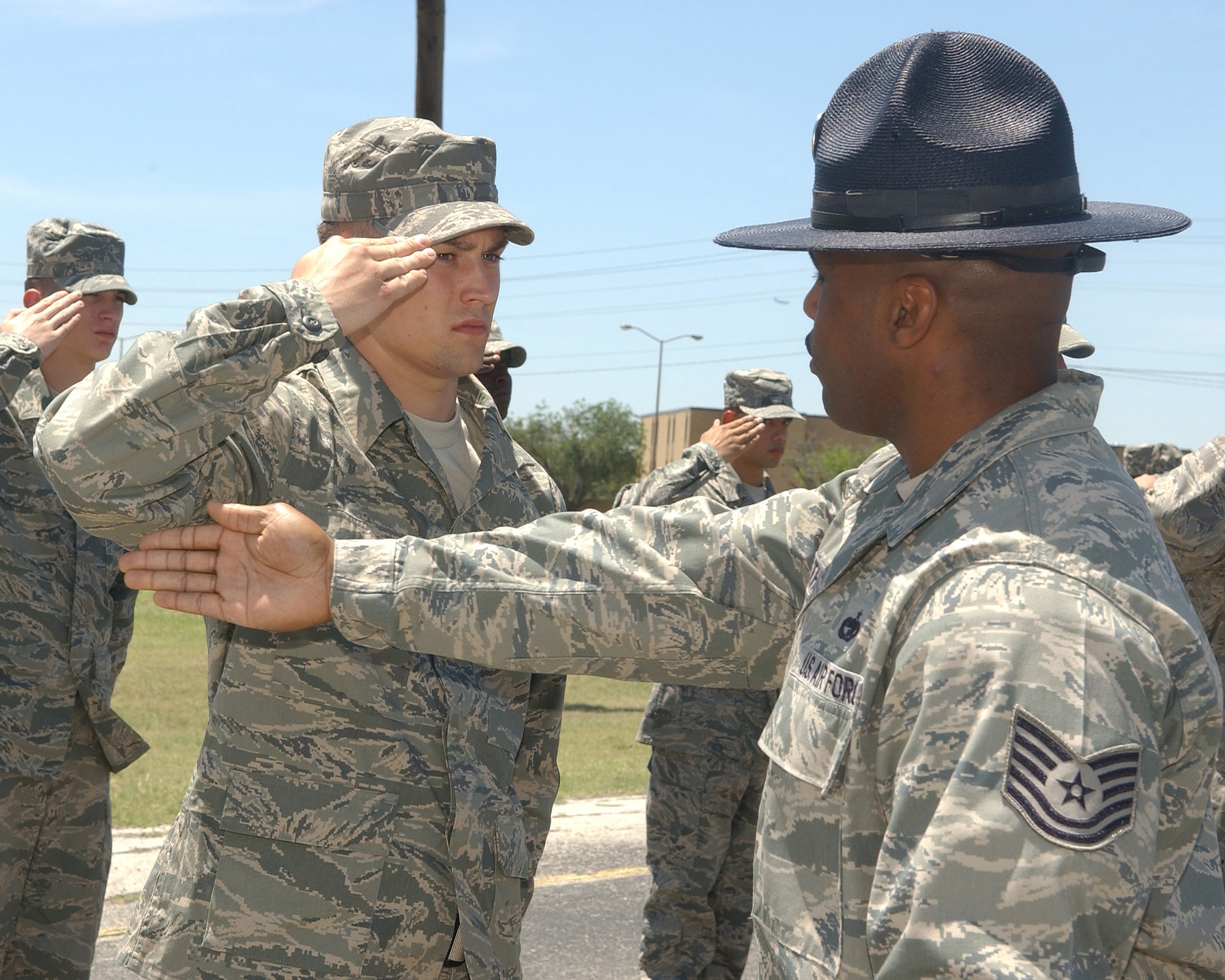 Tech. Sgt. James Thomas, 436th Logistics Readiness Squadron assistant NCO in-charge of vehicle management and currently a Military Training Instructor assigned to the 320th Training Squadron at Lackland Air Force Base, Texas, corrects a trainee giving a salute. Sergeant Thomas will be fulfilling six months of temporary duty to change the lives of 200 or more trainees. (U.S. Air Force photo/ Alan Boedeker)                               