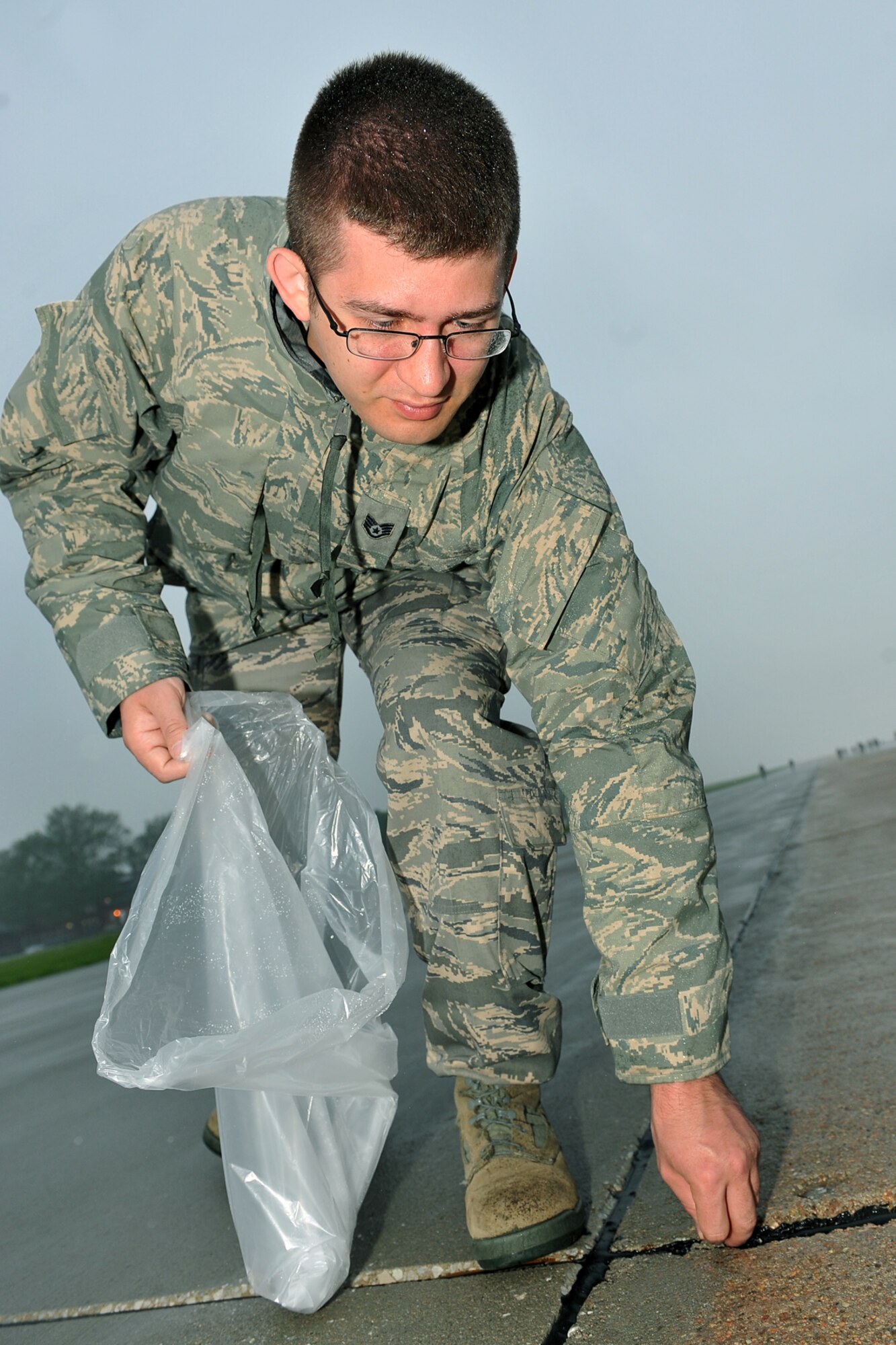 OFFUTT AIR FORCE BASE, Neb., -- Staff Sgt. Brendan Hartzell, 55th Strategic Communications Squadron, picks up rocks during a foreign object and debris walk on the Offutt run way May 26. Removing foreign objects and debris helped ensure the safety of Offutt's aircraft and personnel. U.S. Air Force photo by Charles Haymond