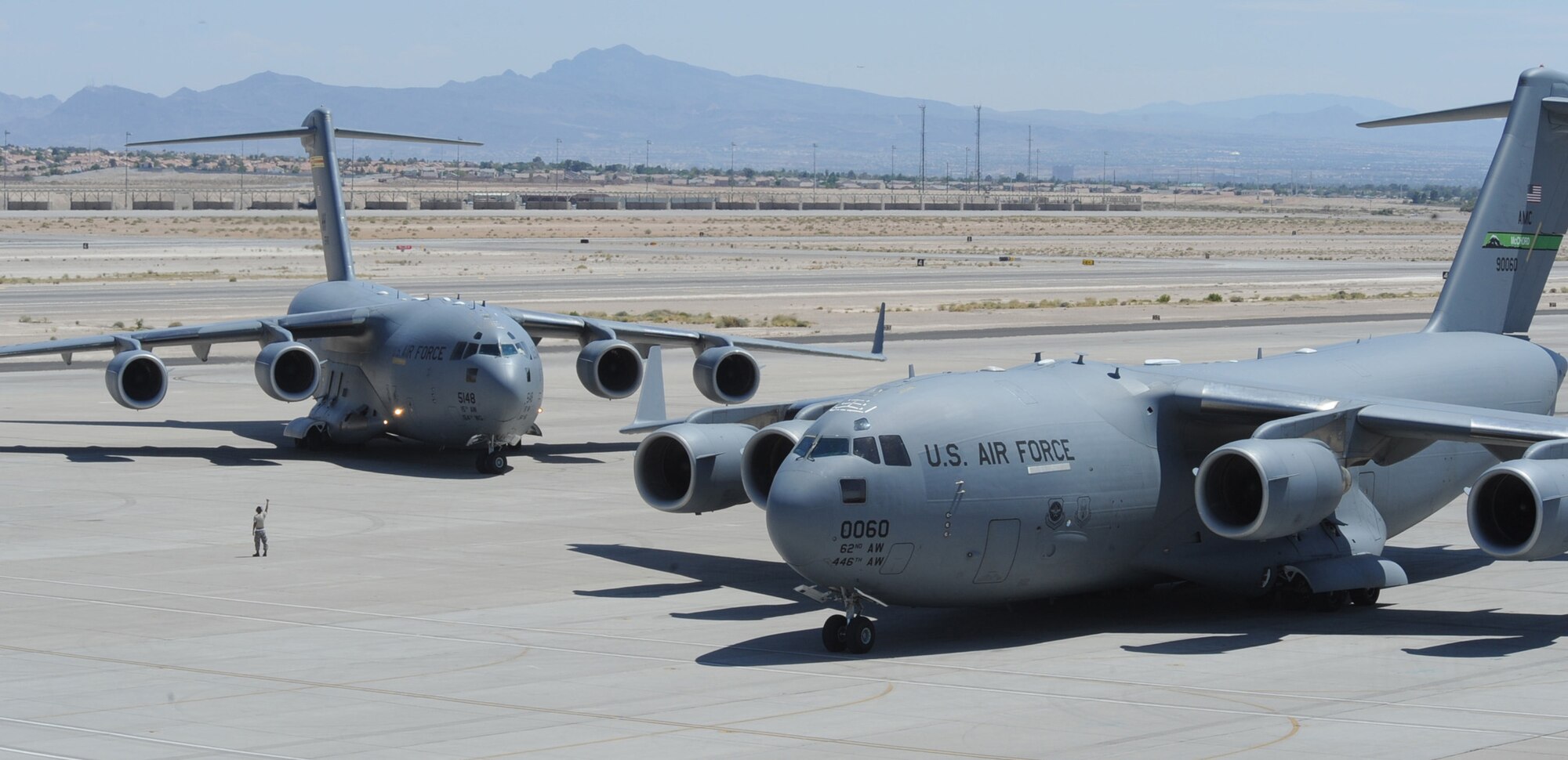 Two C-17 Globemasters taxi in on the Nellis Air Force Base, Nev., flightline May 20 as part of the Mobility Air Forces Exercise.  The 57th Weapons Squadron provides advanced tactical training to C-17 Globemaster aircrew selected to attend the United States Weapons School course here. The six month graduate-level course culminates in a massive airlift mission, called the Mobility Air Forces Exercise. More than 30 airlift assets and hundreds of support personnel from installations across the Air Force participate in the biannual training exercise. (U.S. Air Force photo/Airman 1st Class Stephanie Rubi)