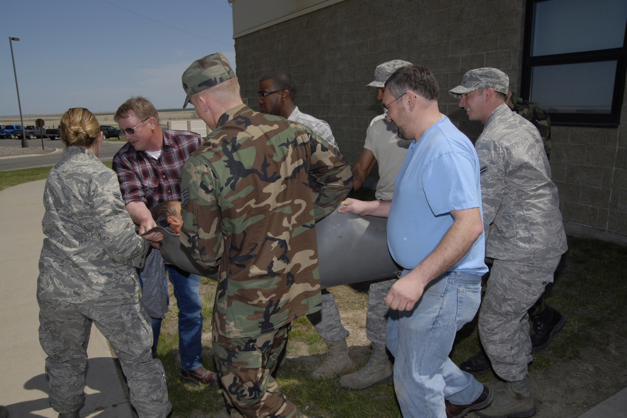 Members of Team Malmstrom carry a natural disaster victim from building 407 during a local operational readiness exercise scenario May 19. The scenario simulated a tornado touching down and causing various damage on the installation. (U.S. Air Force photo/Beau Wade)