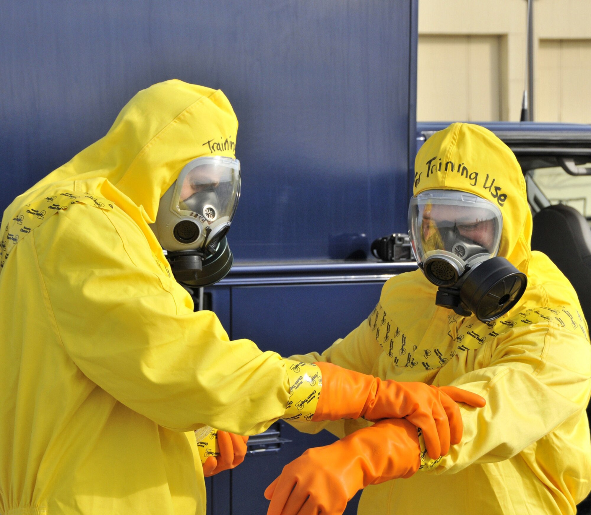 2nd Lt. Brandon Grone seals 2nd Lt. Jared Hostetler's protective suit with tape as the Crisis Management Team prepares to approach a simulated missile convoy accident and measure the air for possible radiation.  (U.S. Air Force by John Turner)